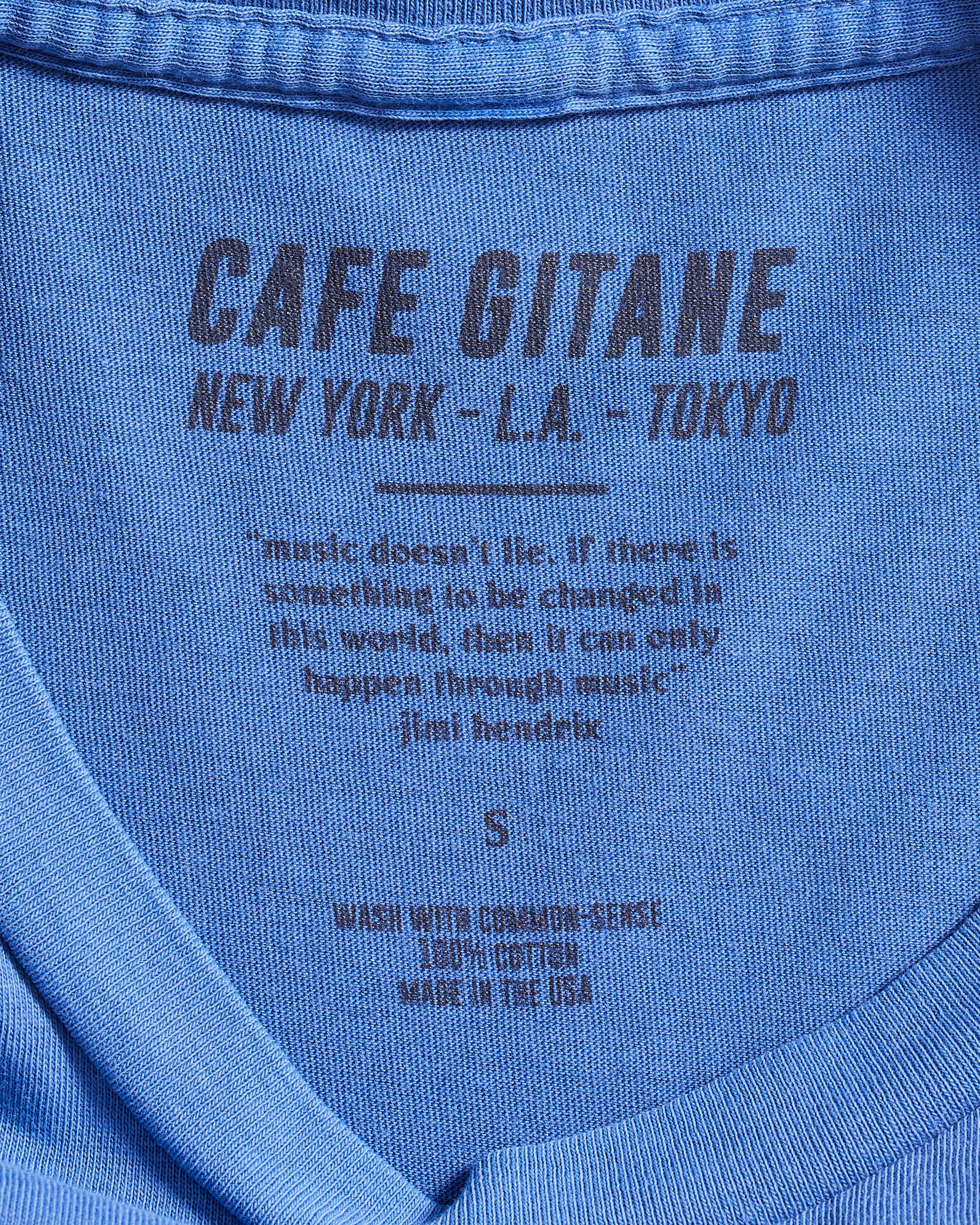 The Cafe Gitane Vintage Wash Embroidered Tee is 100% ring spun cotton. The classic t-shirt in red clay is pigment dyed which means that it has a subtle vintage look and will get more wash the older it gets. It has a printed tag inside shows the care instruction, that it is made in the USA and includes a Jimi Hendrix Quote. It also has the Cafe Gitane logo and stated the cities it has locations in: New York, Los Angeles, and Tokyo. 